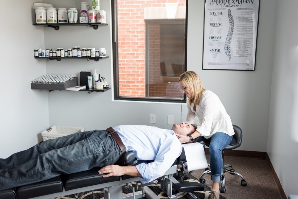 Brand photo of woman chiropractor adjusting a male client at her chiropractor office in Franklin, TN.